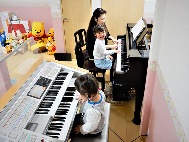 エレクトーンとピアノを3人で弾いている写真